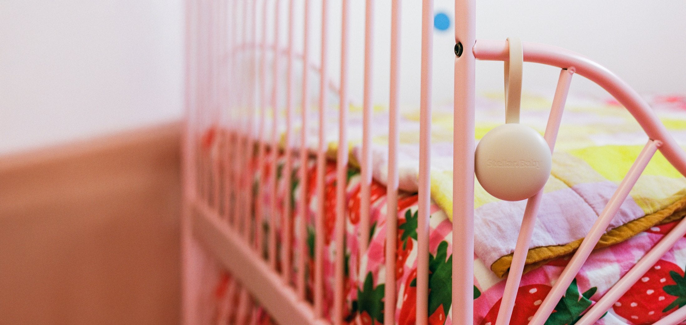 Orbie hanging from a pink cot rail