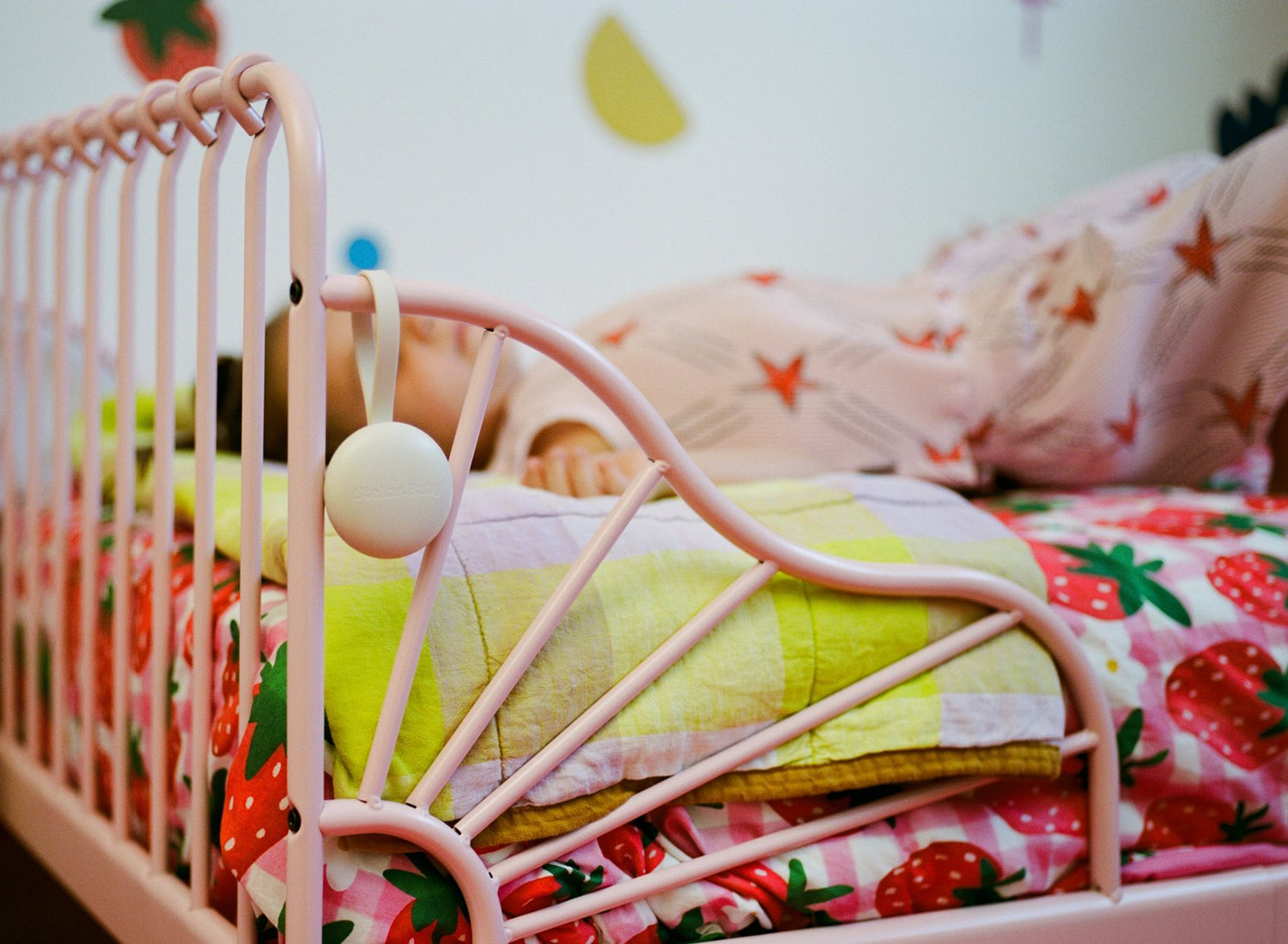 A baby asleep in a cot under a yellow blanket